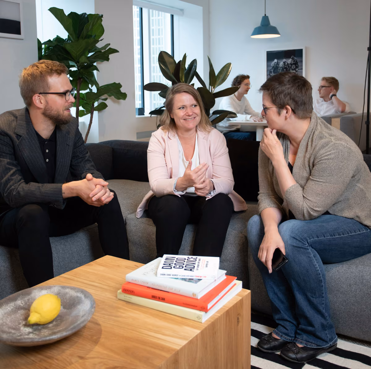 Three people sit together in an office talking