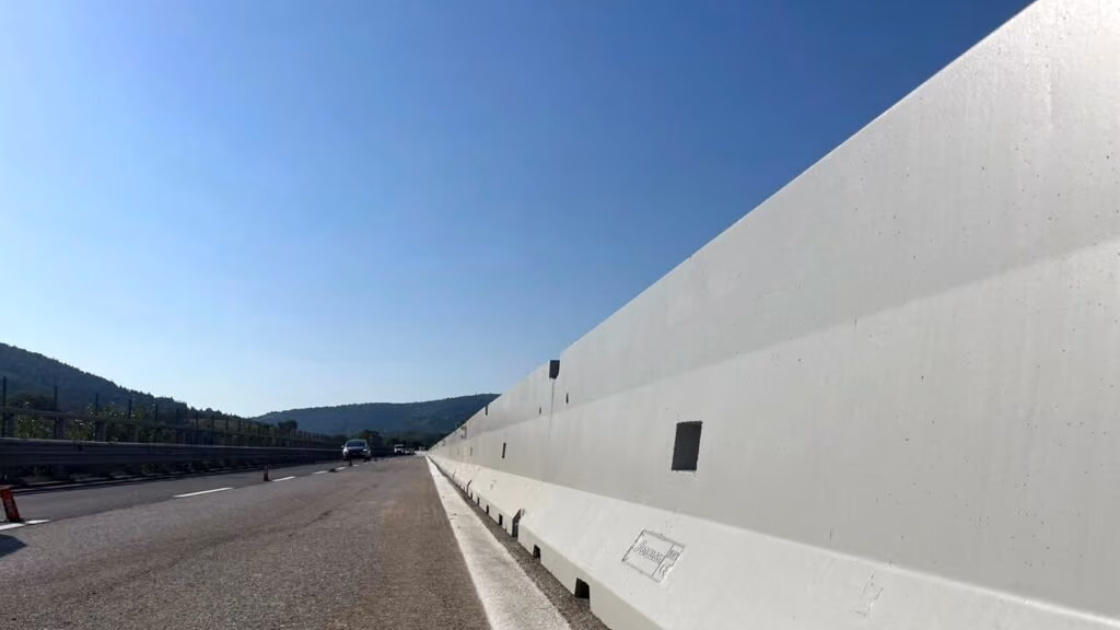 Barriera in calcestruzzo lungo una carreggiata autostradale, in controluce
