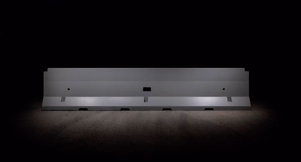 Barriera spartitraffico in calcestruzzo illuminata su sfondo nero