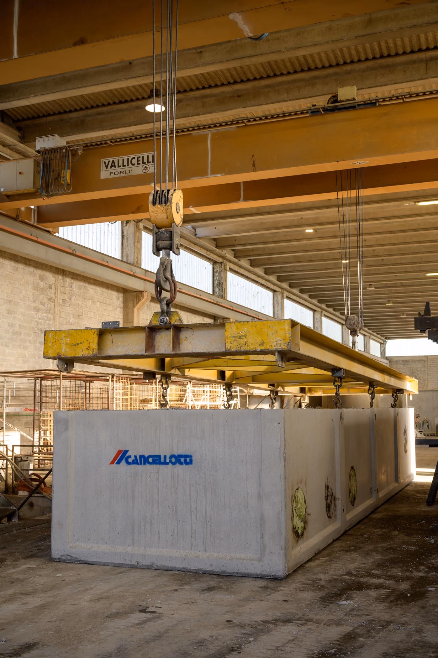 Vasca prefabbricata in calcestruzzo sospesa a un carroponte all'interno dello stabilimento