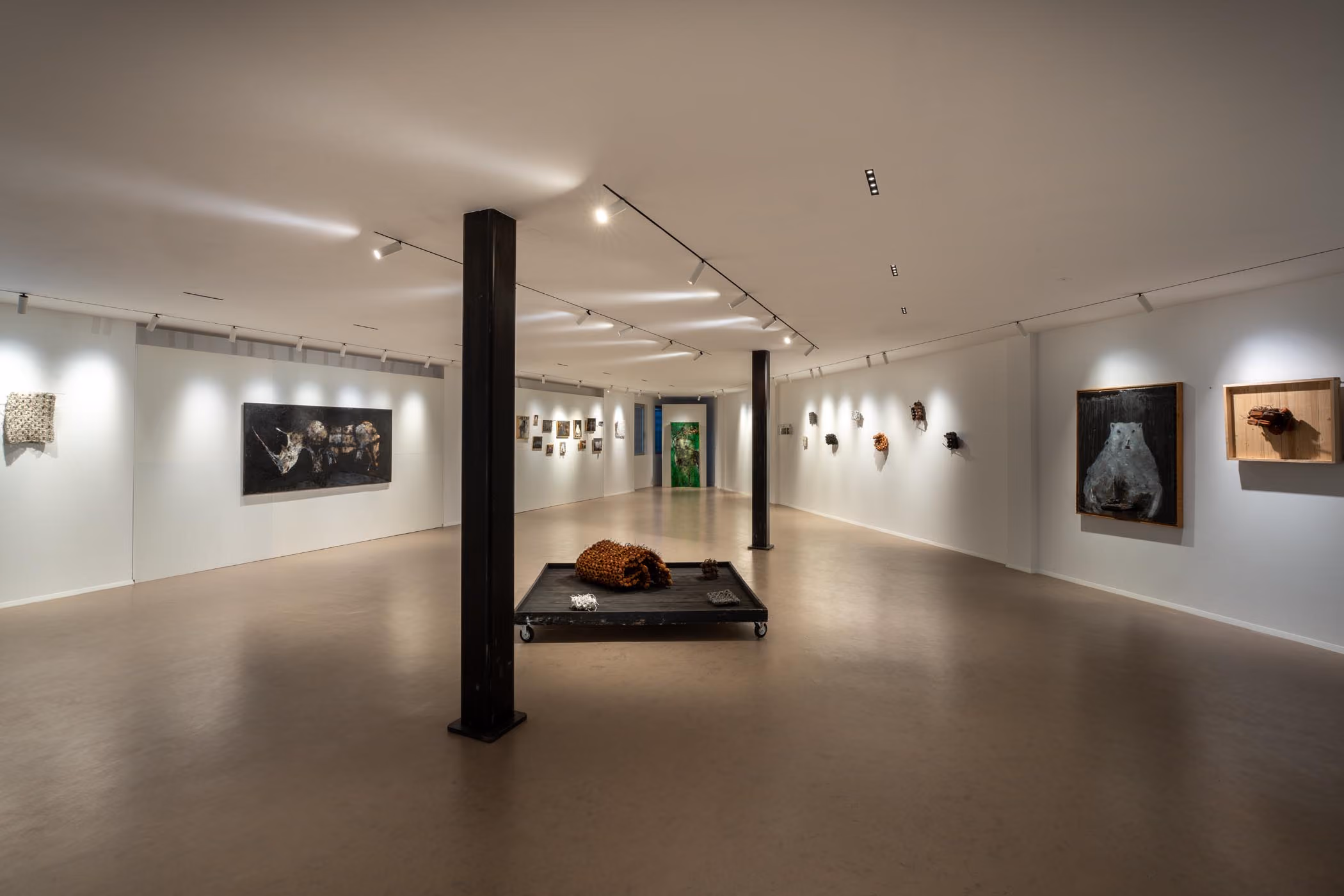 Sala espositiva luminosa con opere alle pareti e una scultura su un basamento