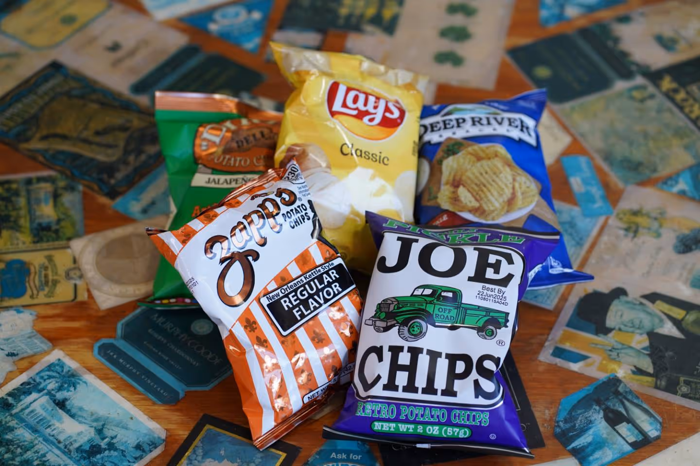 Five different bags of potato chips on a colorful table with various labels and colors.