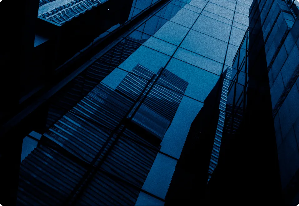 Reflection of tall skyscrapers on the glass facade of another modern building at night.