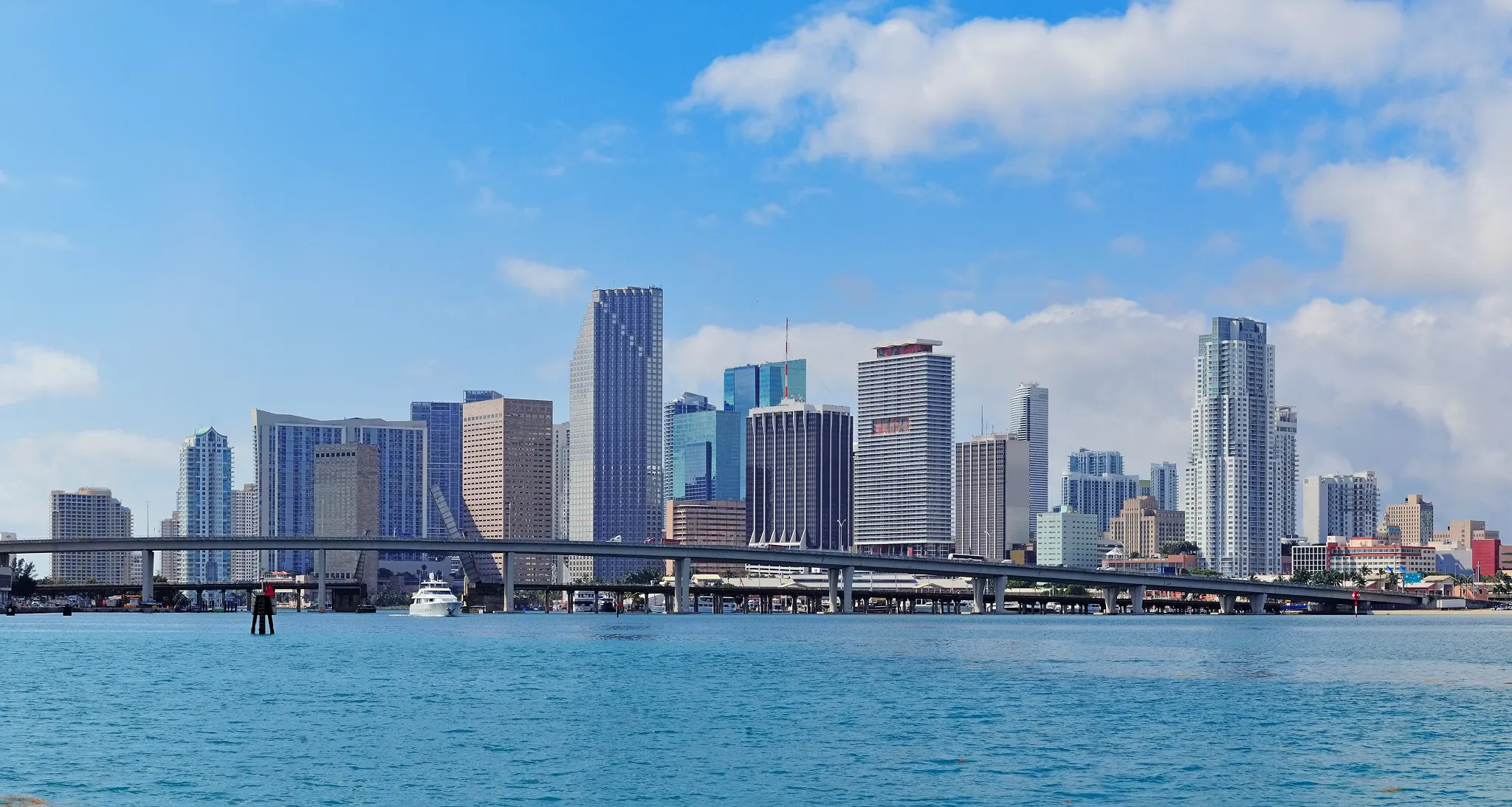 Aerial view of Miami coastline with beach, ocean, high-rise buildings, and inland waterway.
