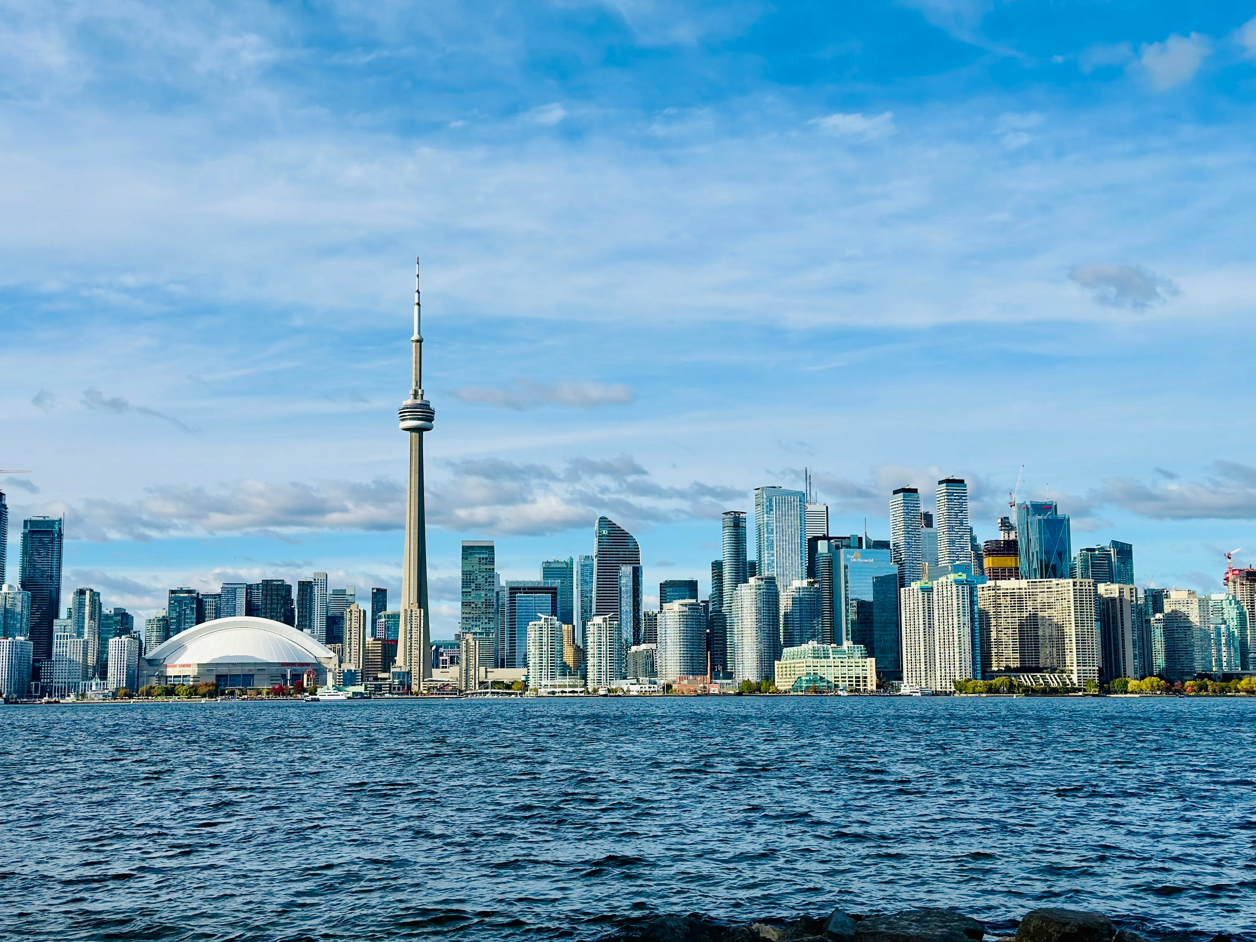 Toronto skyline featuring CN Tower and surrounding high-rise buildings under a blue sky.