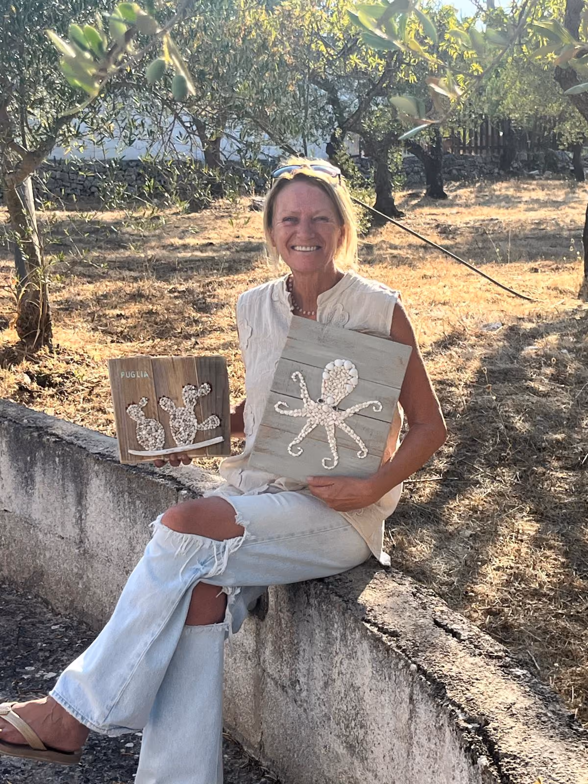 Nens holding her handmade artworks in an olive grove in Puglia