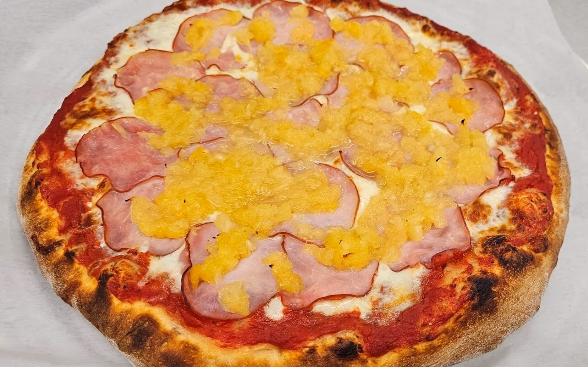 Half sausage half cheese thin crust pizza with tomato sauce in a takeout cardboard box.