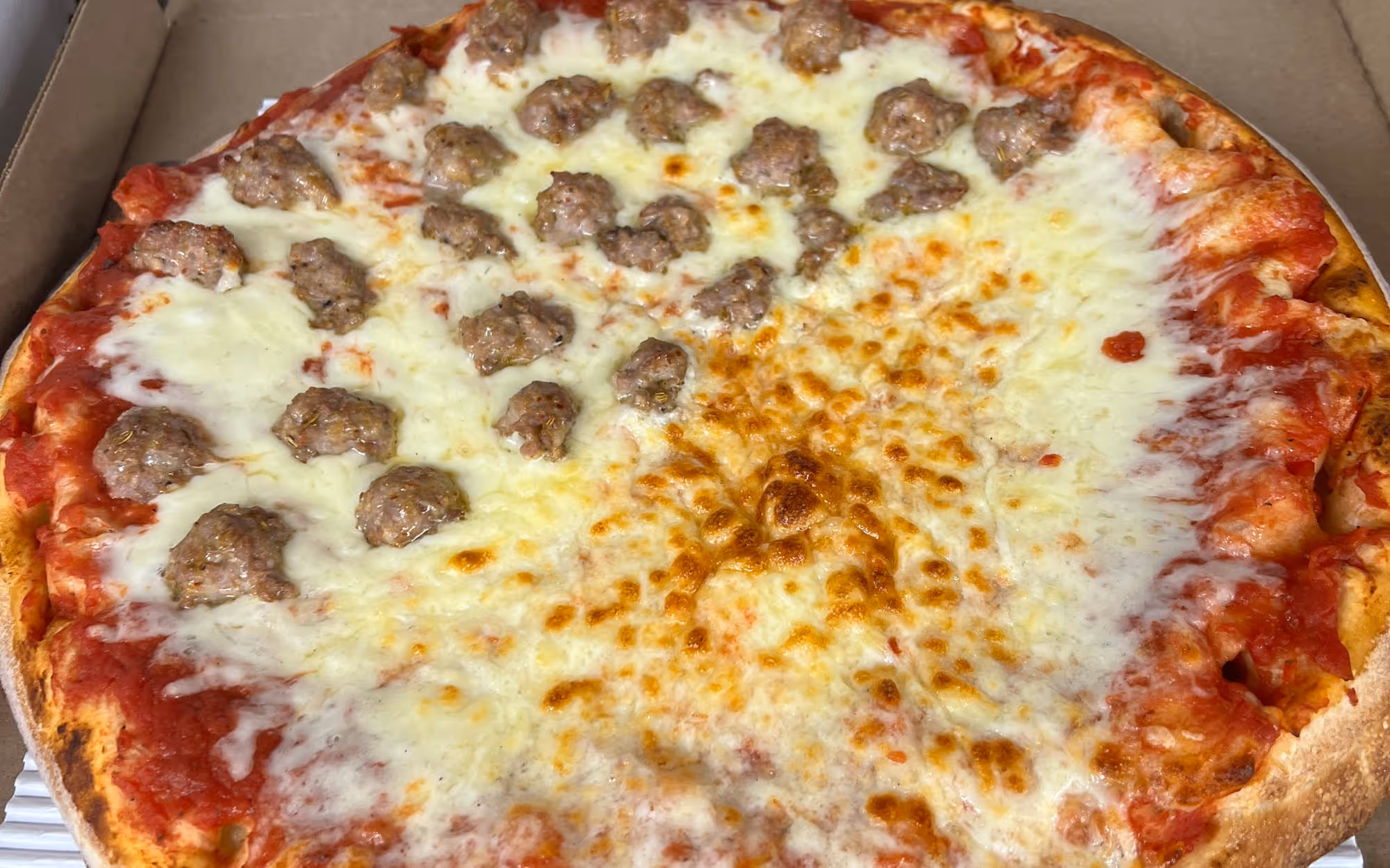 Large thin-crust pizza with half sausage and half plain cheese toppings, melted mozzarella, and red tomato sauce.