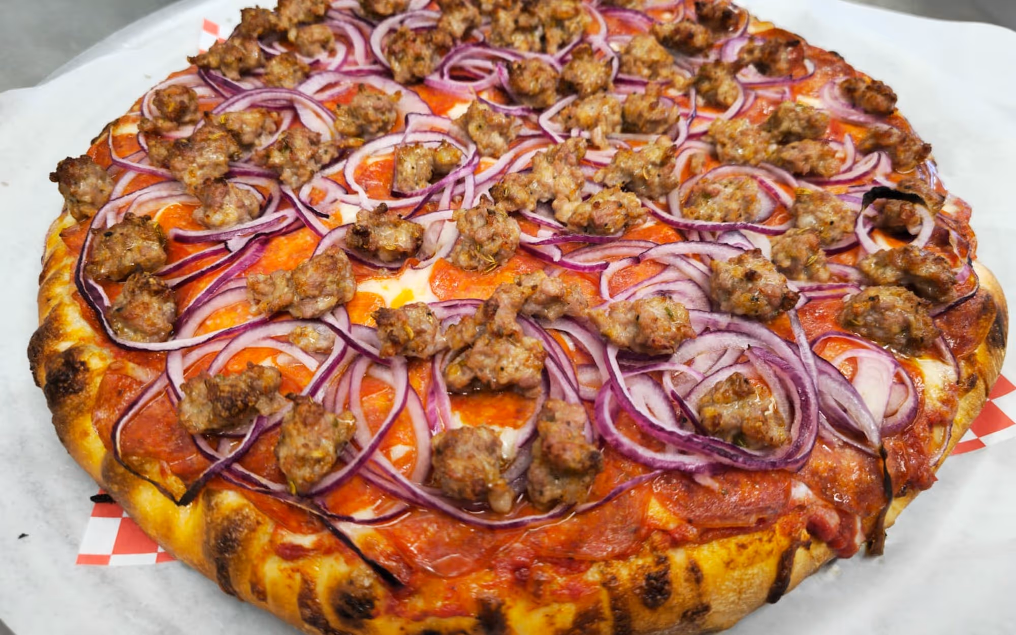 Freshly baked thin crust pizza topped with crumbled Italian sausage, sliced red onions, and melted mozzarella cheese.