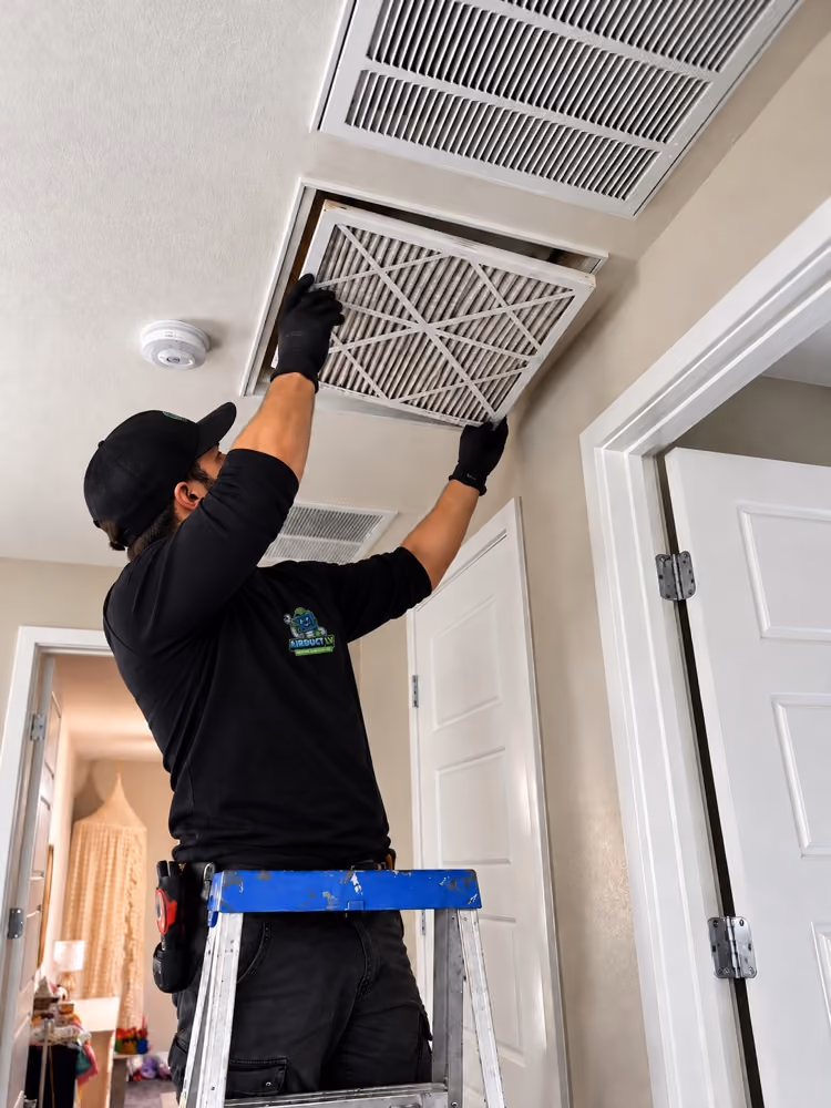Air Duct LV technician fitting a clean air filter into a return vent.