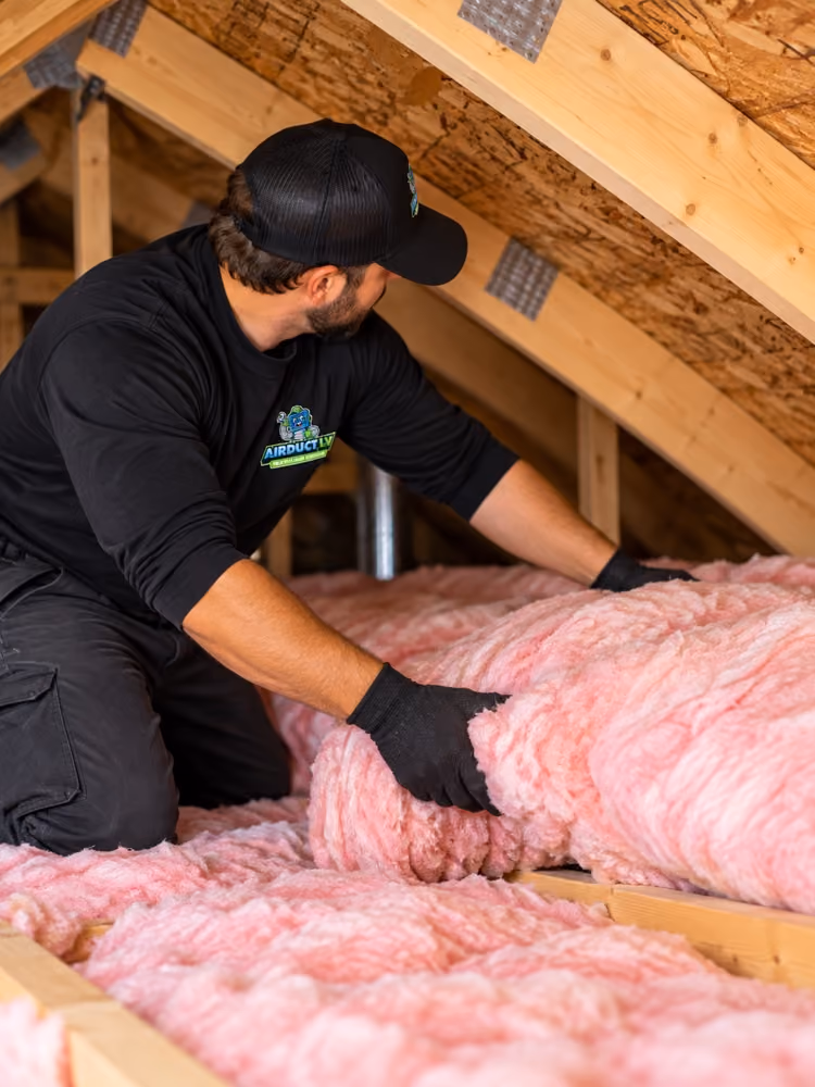 Air Duct LV technician laying batt insulation between attic joists.