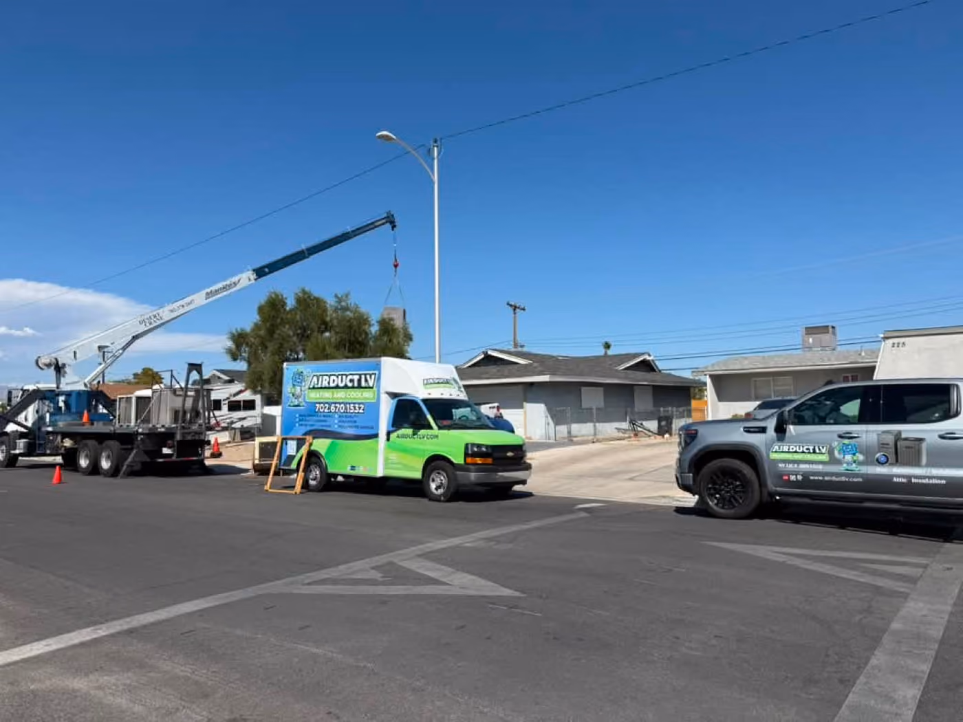 An Air Duct LV truck on site beside a boom lift on a commercial job.