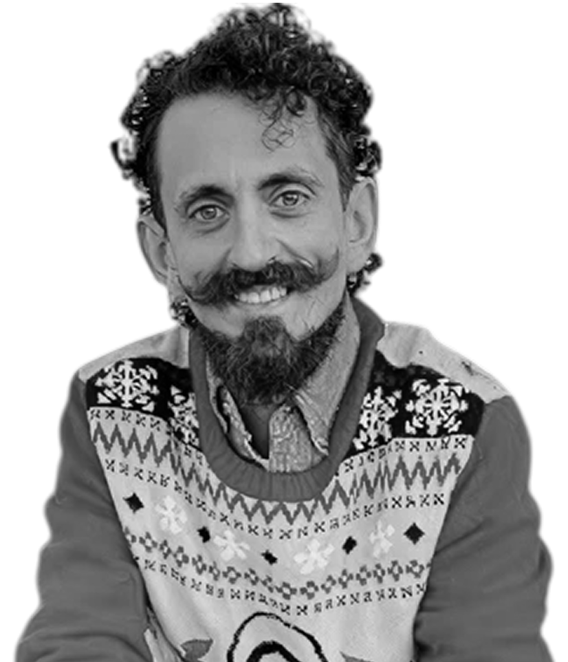Man with curly hair and a beard wearing a patterned sweater.