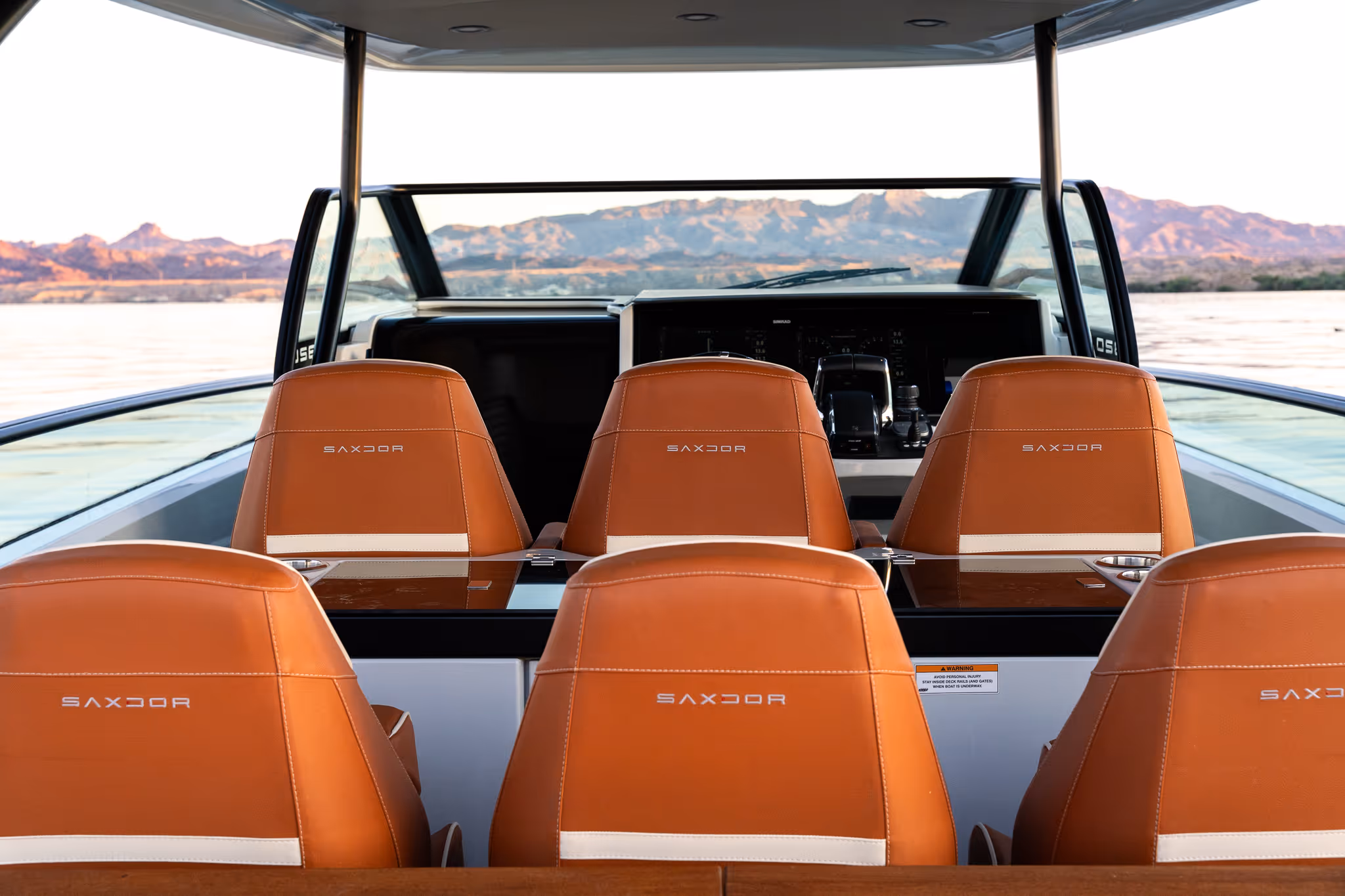 Six brown leather SAXDOR boat seats facing front with a dashboard and mountains in the background.