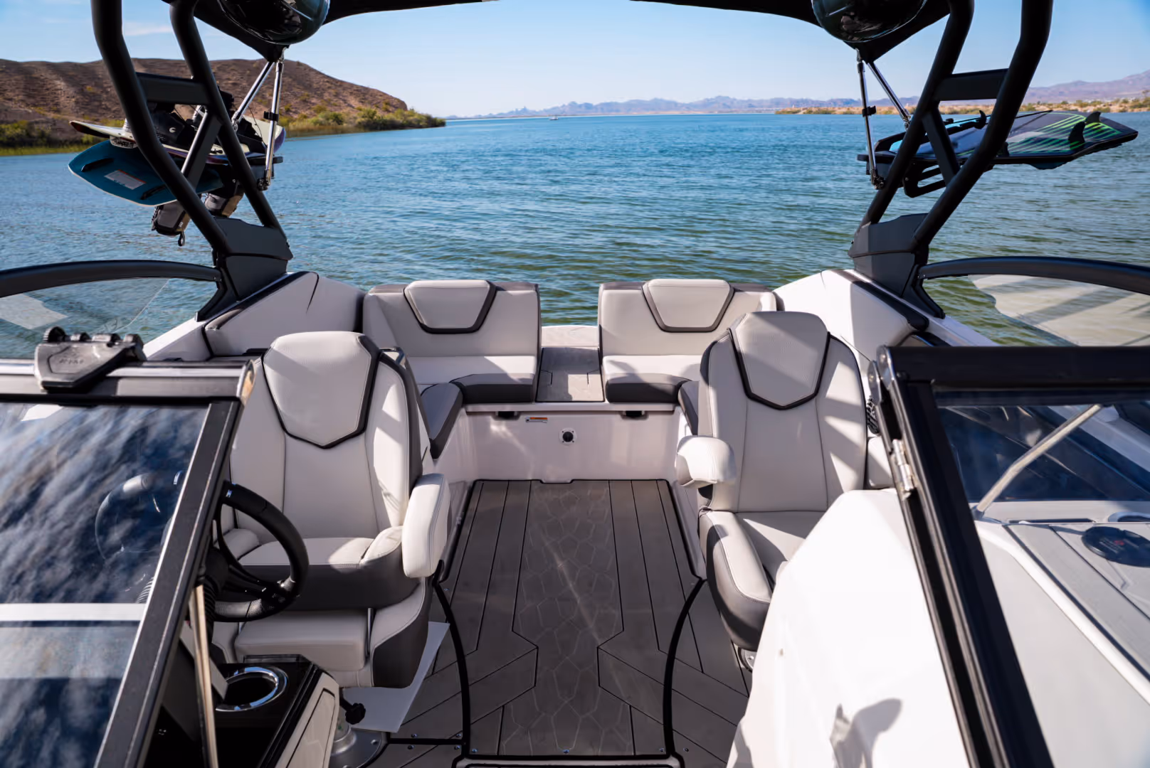 Interior of boat with two cushioned seats and bench facing a lake with hills in the background.
