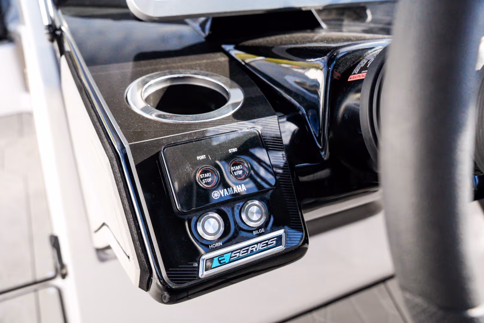 Close-up of Yamaha E Series boat control panel with start/stop, horn, and bilge buttons next to a cup holder.