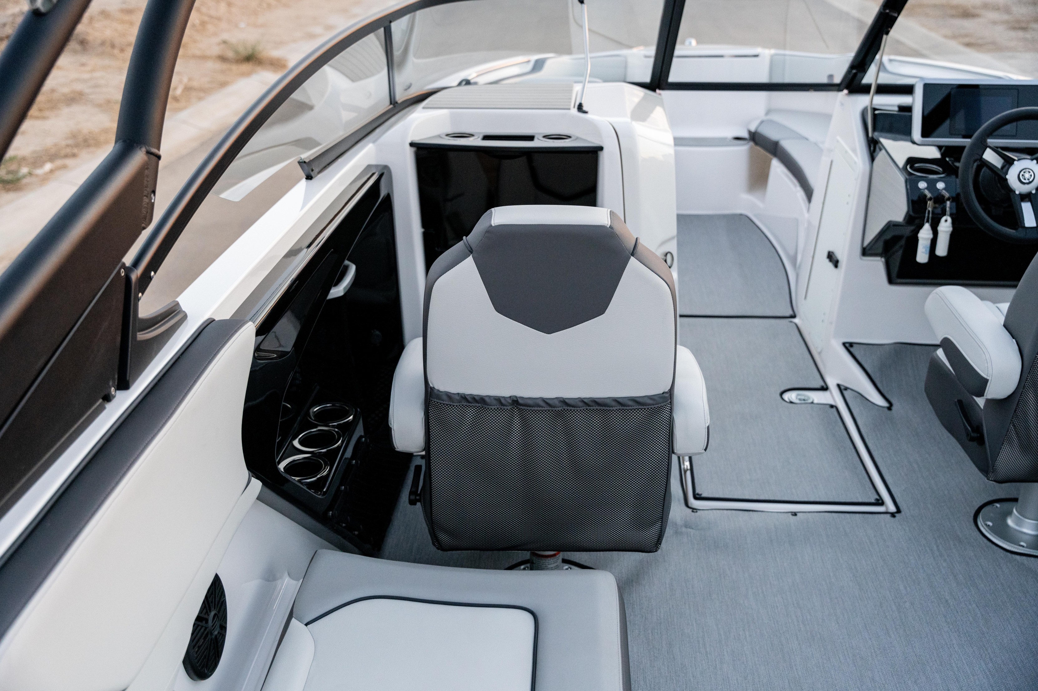 Interior of a modern boat showing seats, cup holders, steering wheel, and open deck space.