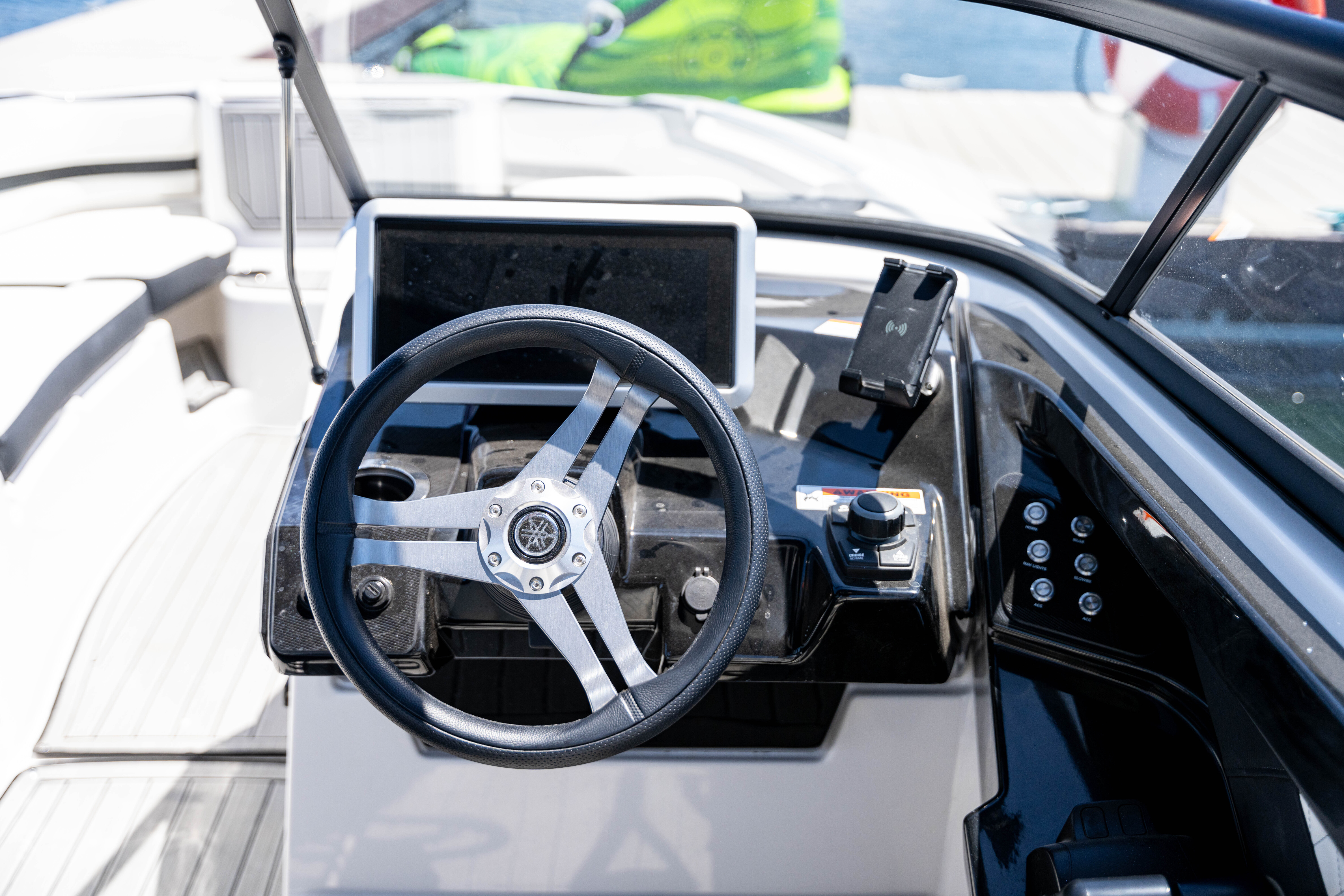 Steering wheel and control panel with touchscreen on a modern boat helm station.