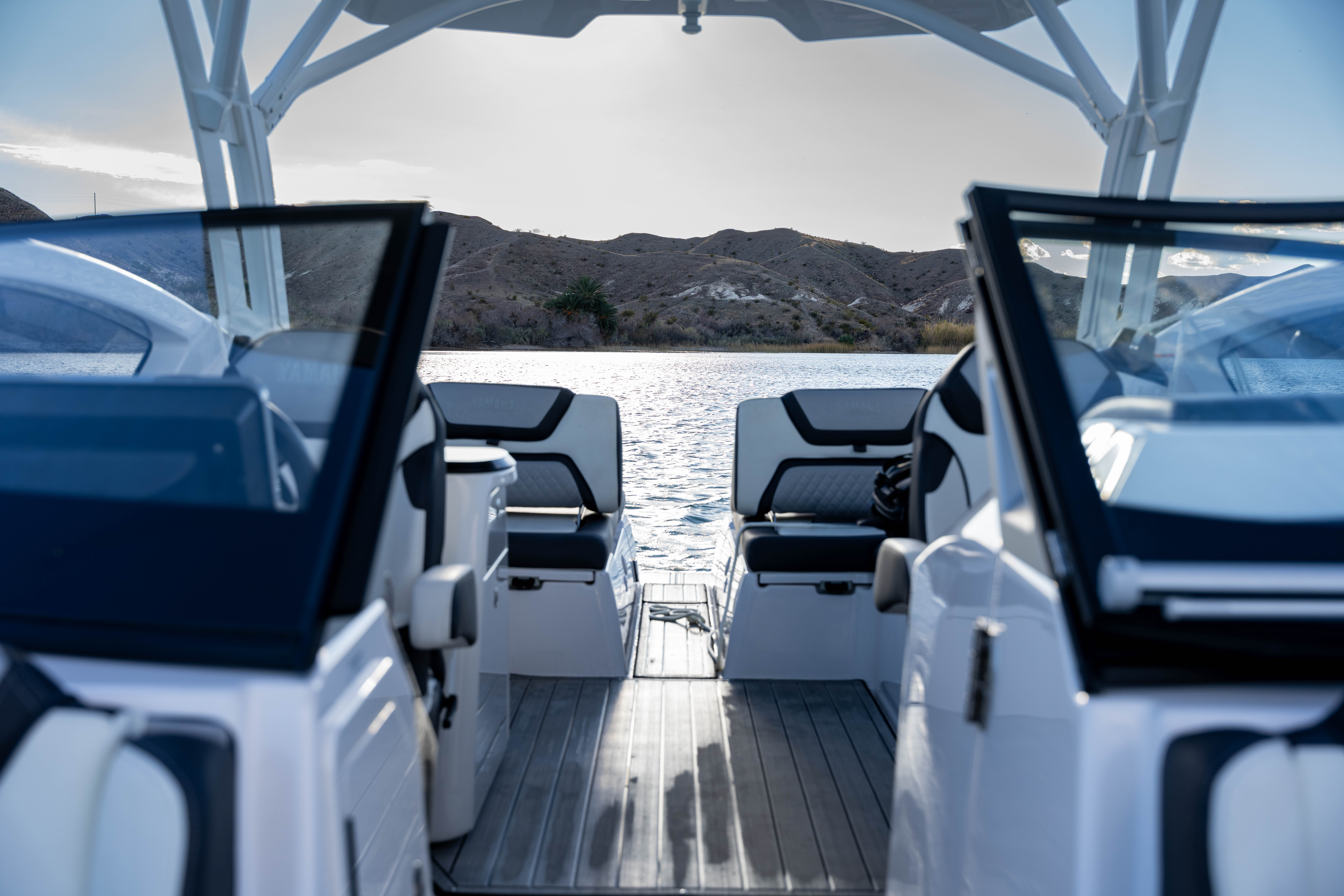 View from inside a boat looking out at calm water and hills under a clear sky.