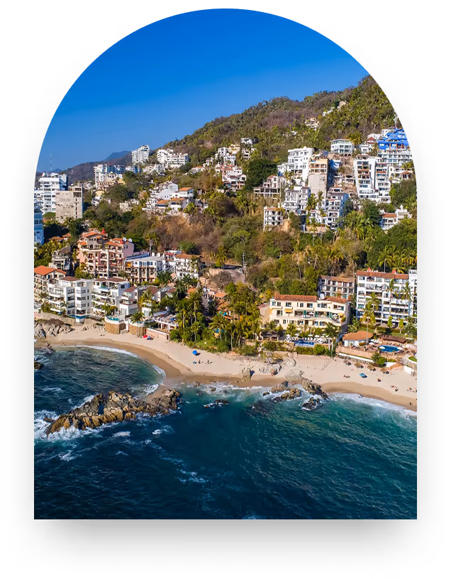 View of Lower Conchas Chinas through an arched window — a hillside of private estates above a sandy cove in Puerto Vallarta, ten minutes south of Old Town.