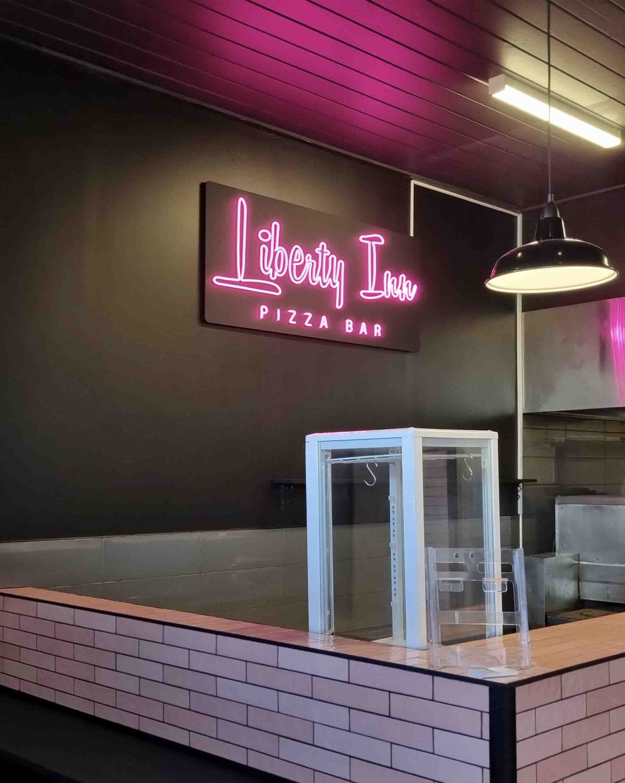 a pink custom neon sign that says Liberty Inn Pizza. Custom neon sign by MC Grafix and Signs Drouin