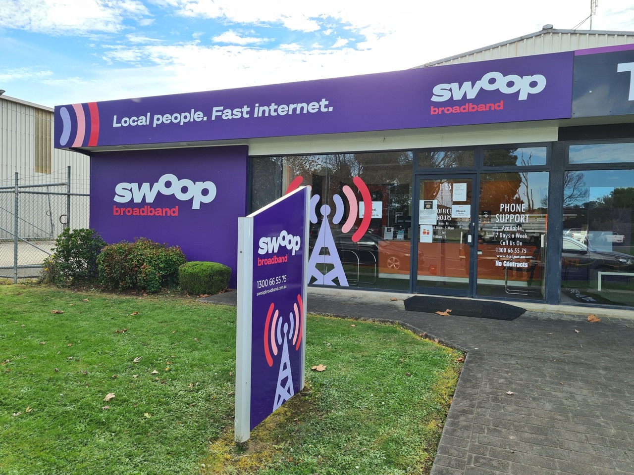 A purple sign covered shopfront with grass infront of it for Swoop Broadband Warragul, signwriting by MC Grafix Warragul