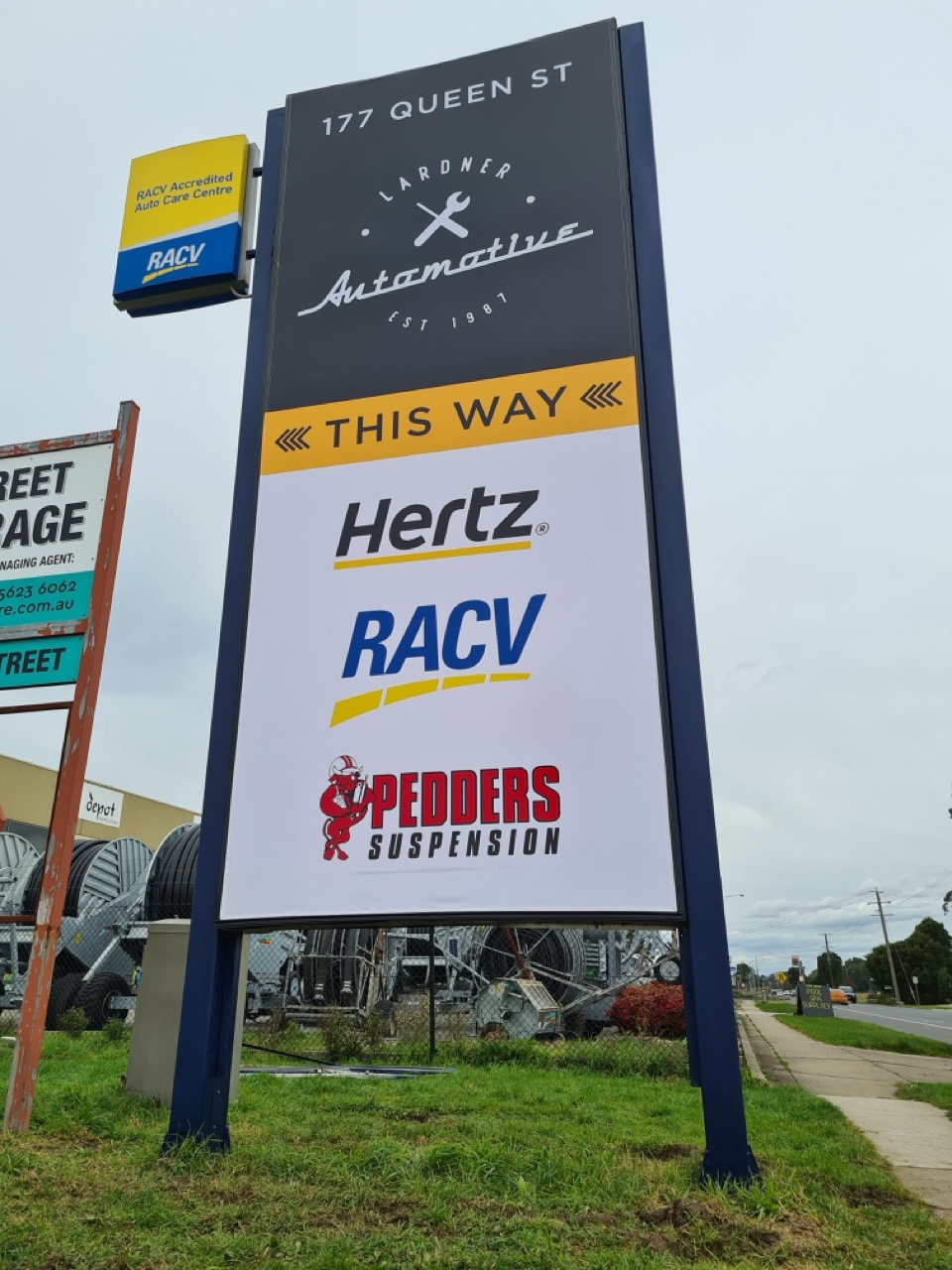 A vertical billboard sign lit up that reads Lardner Automotive