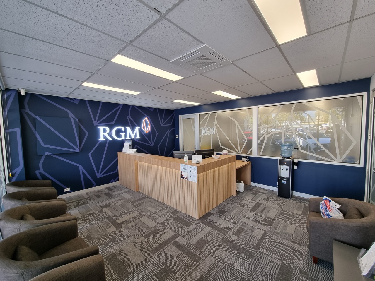 A reception area for RGM Financial showing a desk with multiple chairs and interior sign writing by MC Grafix