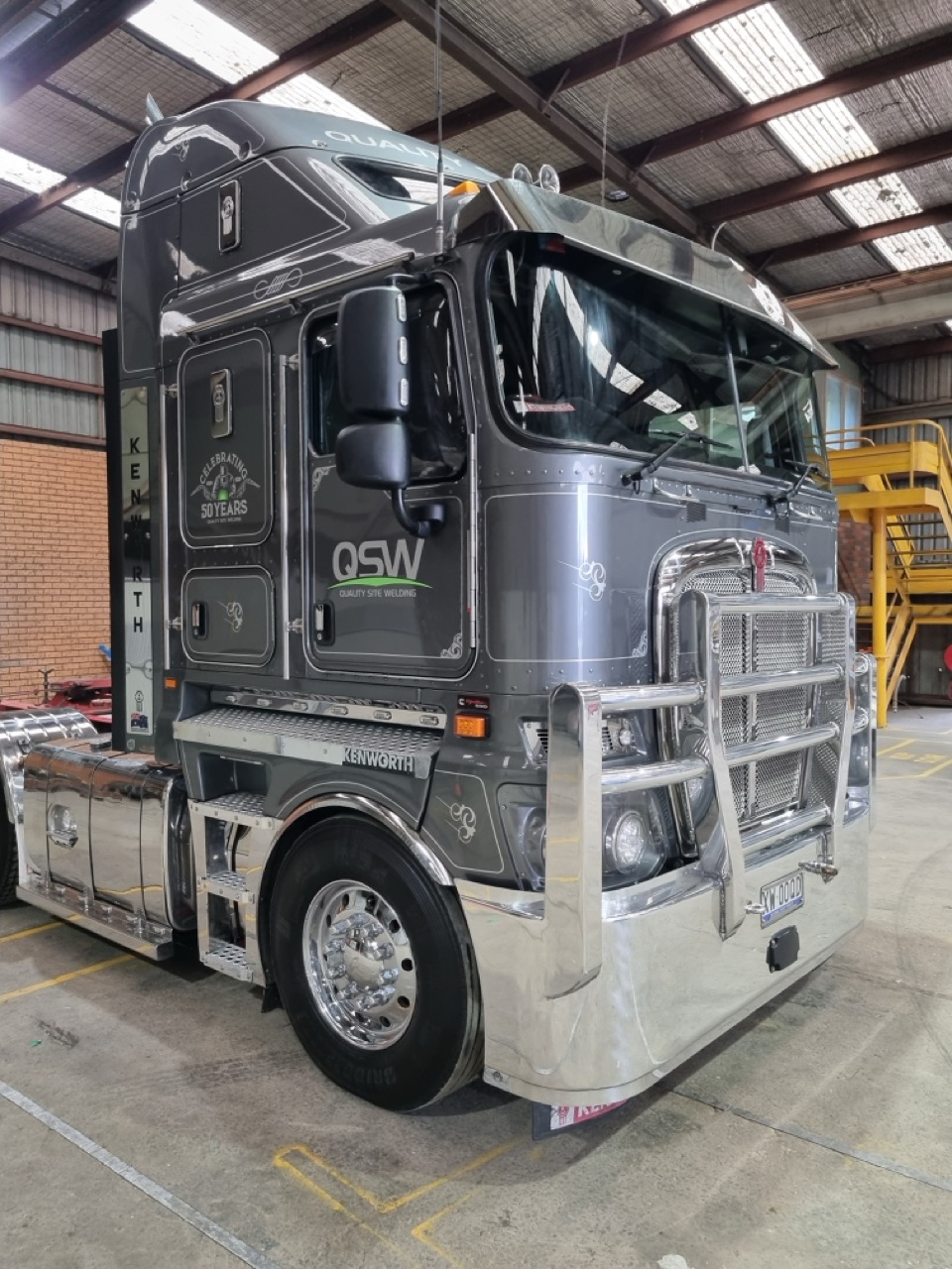 A large truck parked in a factory with sign writing by MC Grafix 
