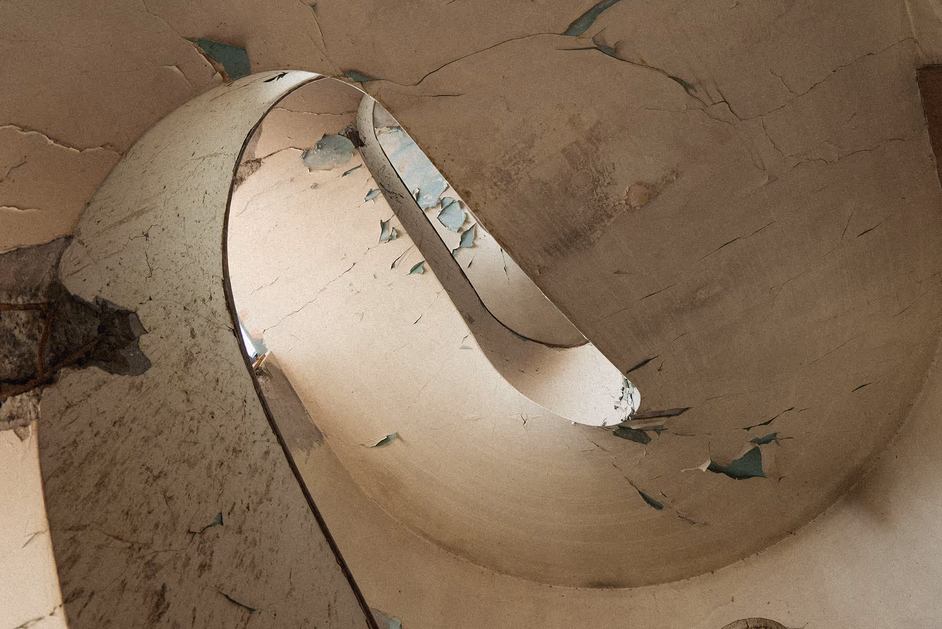 Close-up of peeling paint on a curved, cracked surface with exposed layers underneath.
