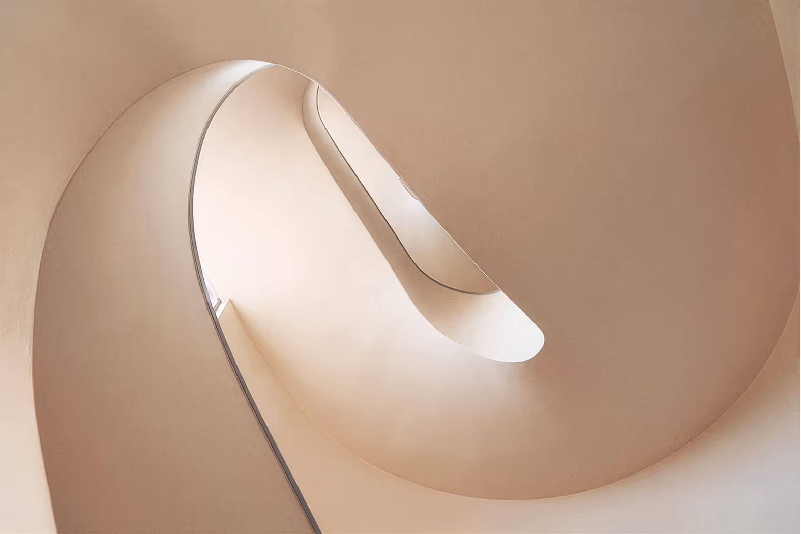Abstract curved beige staircase viewed from below with smooth flowing lines and soft light.