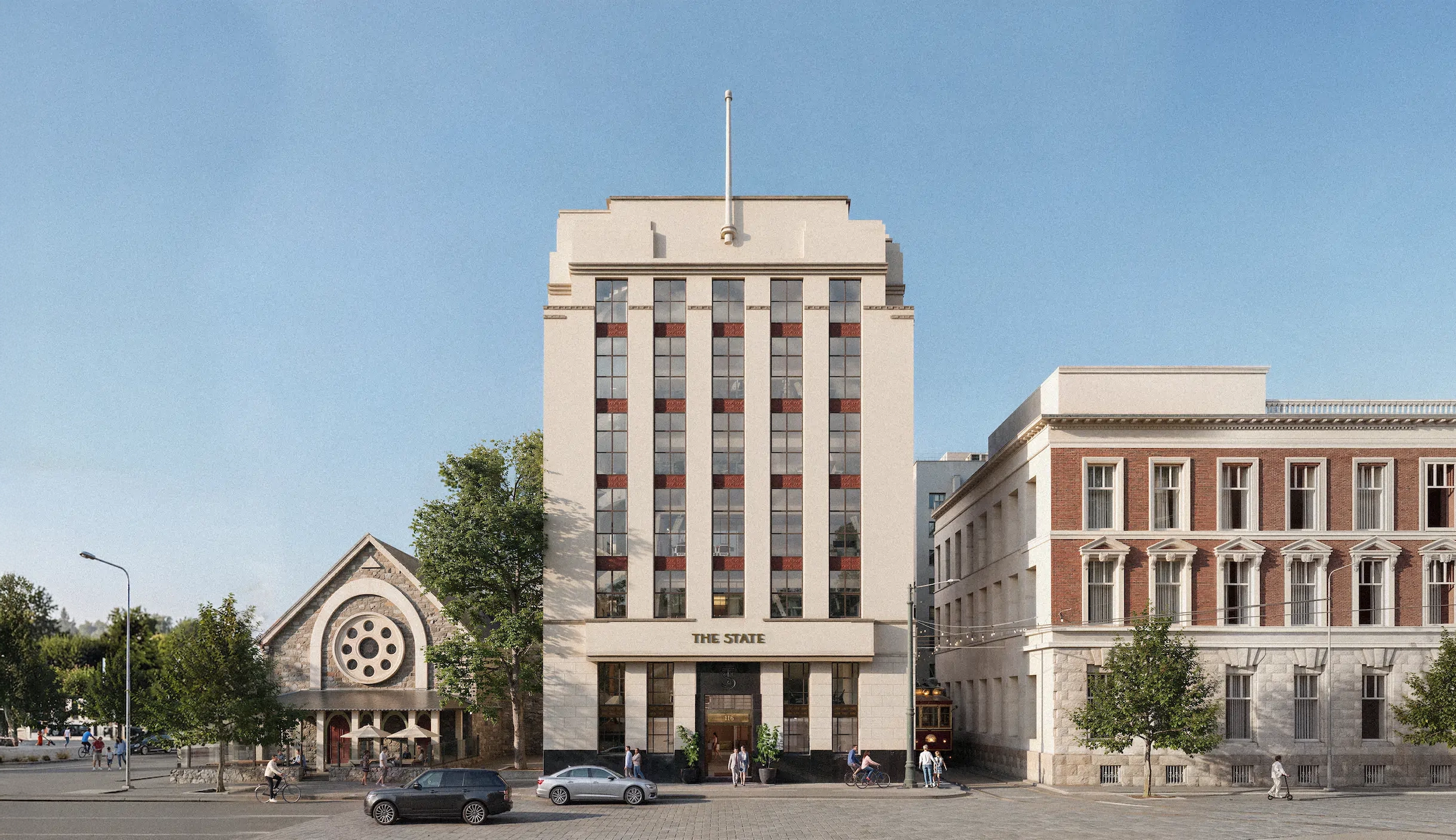 Front view of The State building, a tall beige structure with vertical windows and a flagpole on top, flanked by a stone church with circular window on the left and a red-brick building on the right, with people, cars, bicycles, and a tram on the street in front.