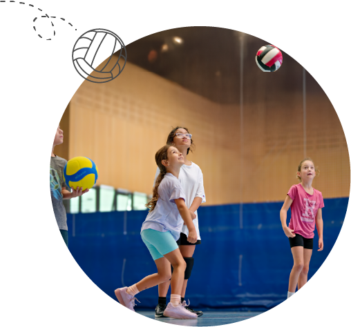Three girls in gym playing volleyball, preparing to hit a ball in mid-air inside the indoor sports centre at All Saints College Bullcreek