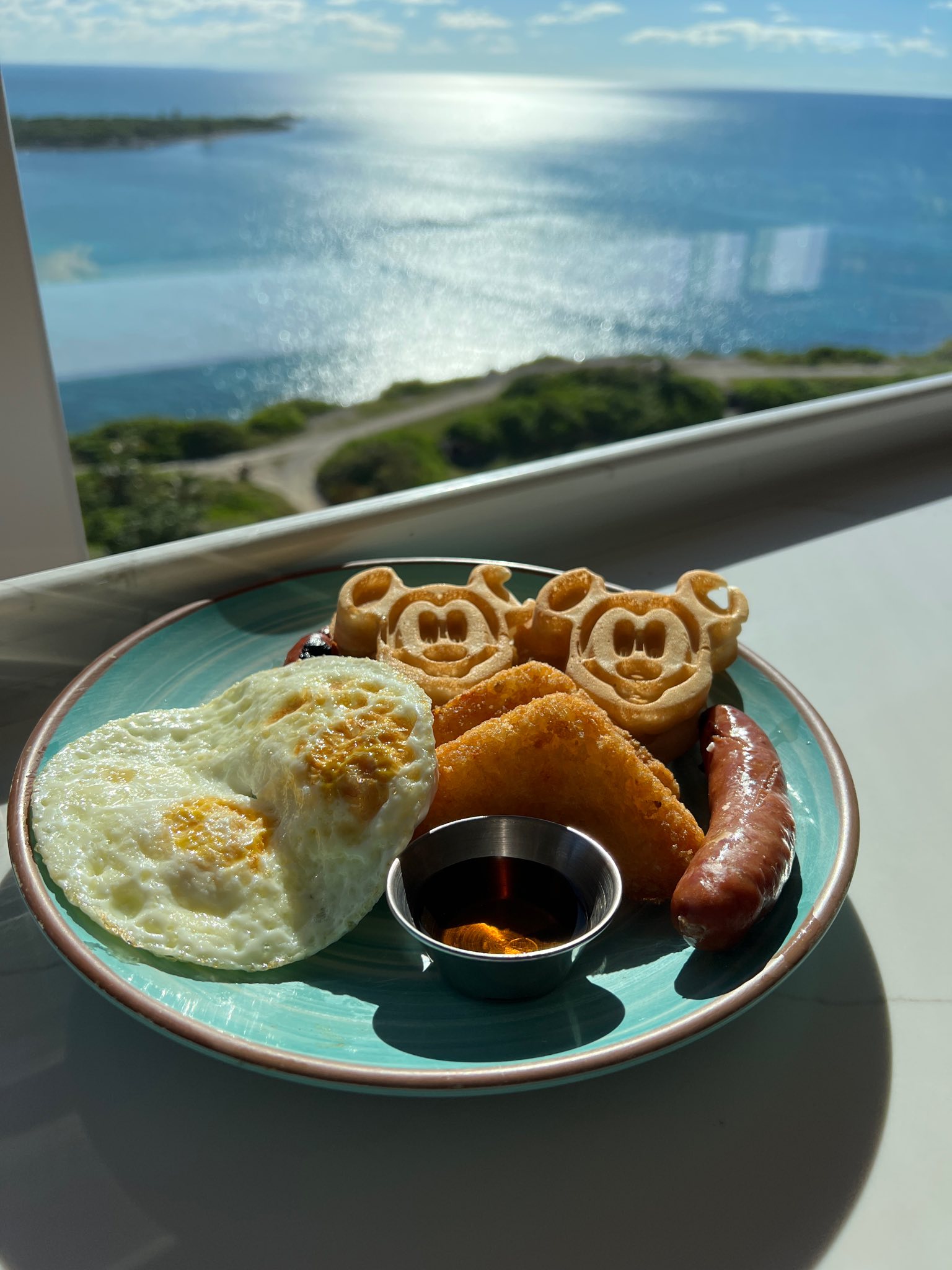 Gluten free breakfast plate with gluten free Mickey Waffles on a Disney Cruise ship overlooking the water