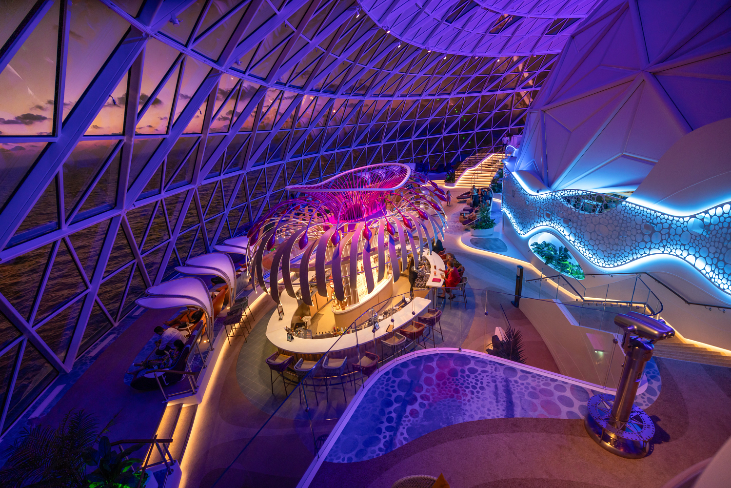 The Overlook lounge at the front of the AquaDome on Royal Caribbean's Icon of the Seas, with seating facing floor to ceiling windows over the ocean.