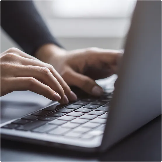 Close-up of hands typing on a laptop.