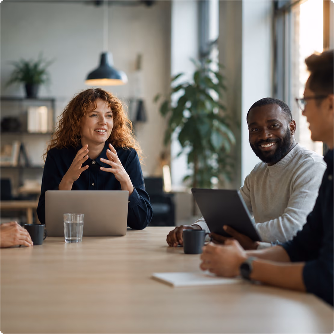 Procurement professionals discussing purchasing workflows together around a laptop.