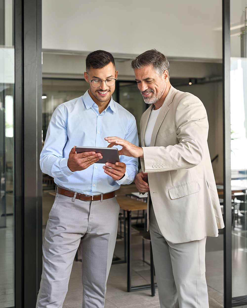 Two male brokers smiling and looking at a tablet, showcasing how to partner with Bizcap to finance small businesses.