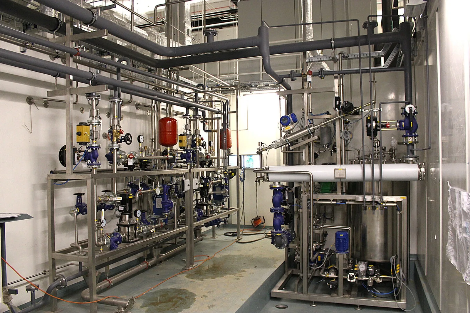 Csővezetékek és nyomástartó edény egy technológiai helyiség sarkában