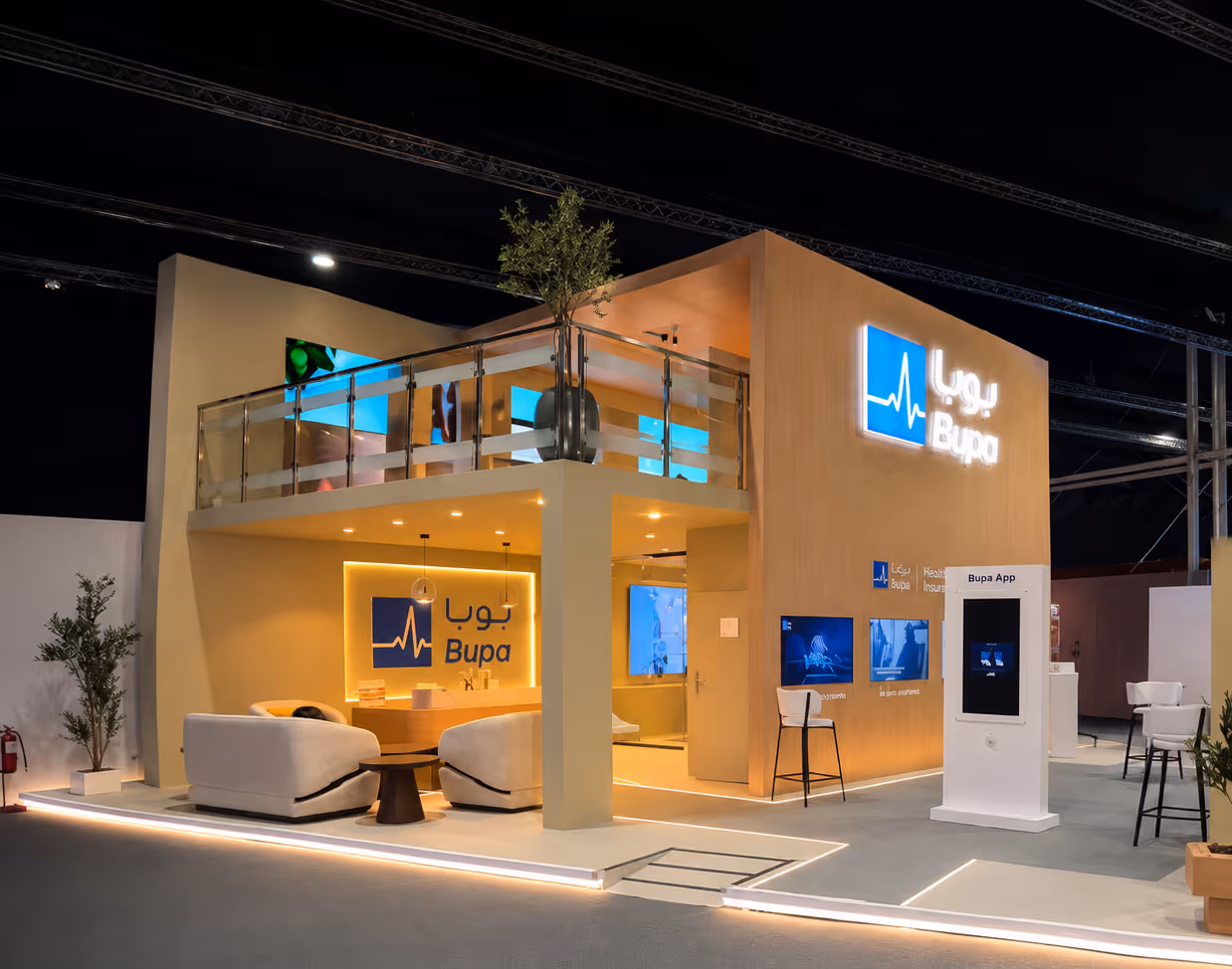Modern two-story Bupa booth with seating area, screens, and Bupa health insurance branding at event.
