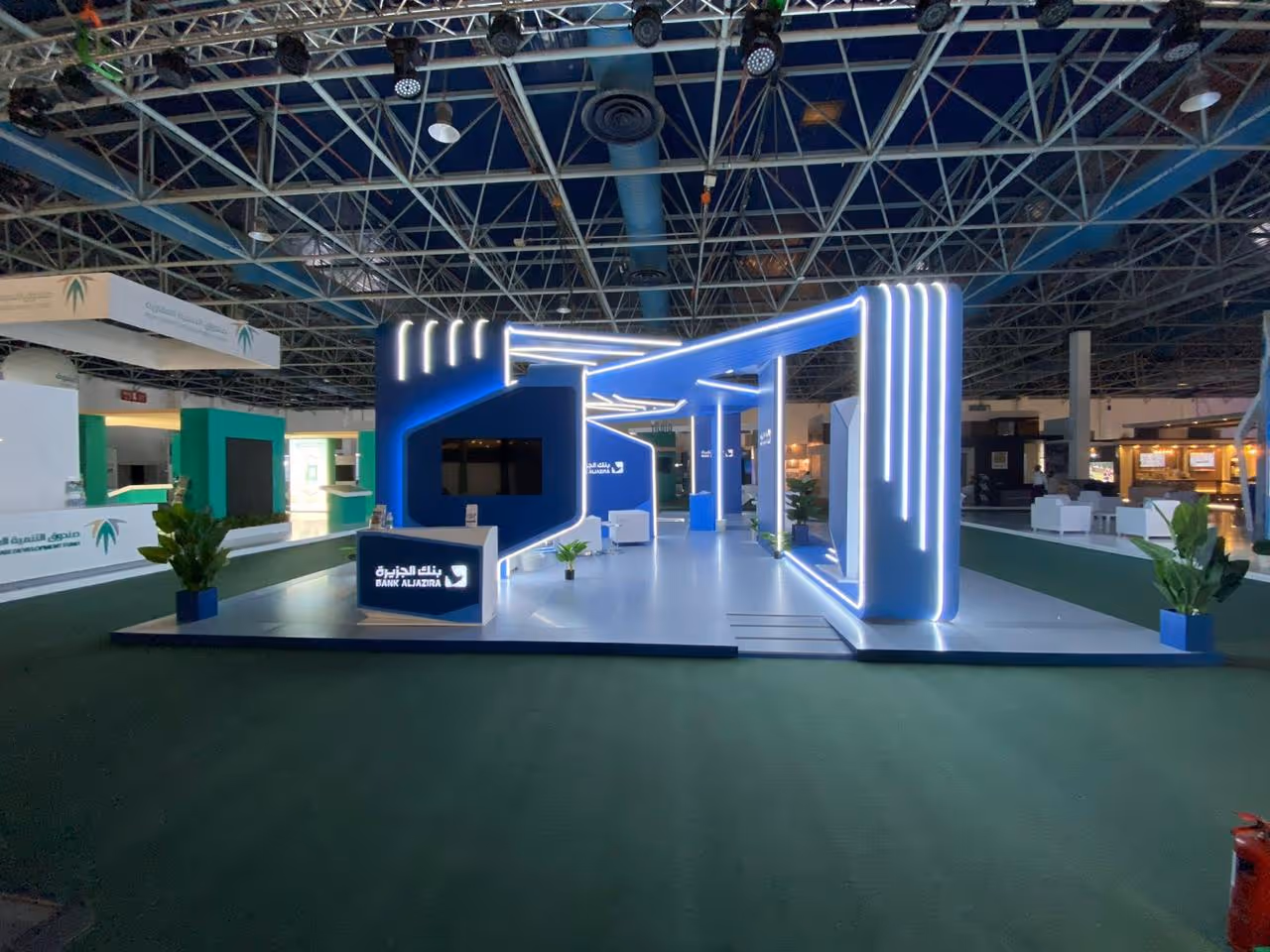 Modern Bank Aljazira exhibition booth with blue and white lights in a large indoor venue.