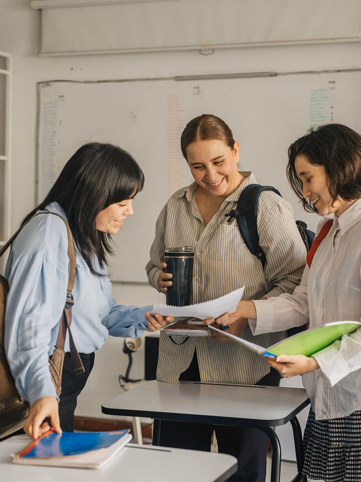 Drei Frauen lächeln gemeinsam über Kursunterlagen in einem Deutschkurs in Fürth