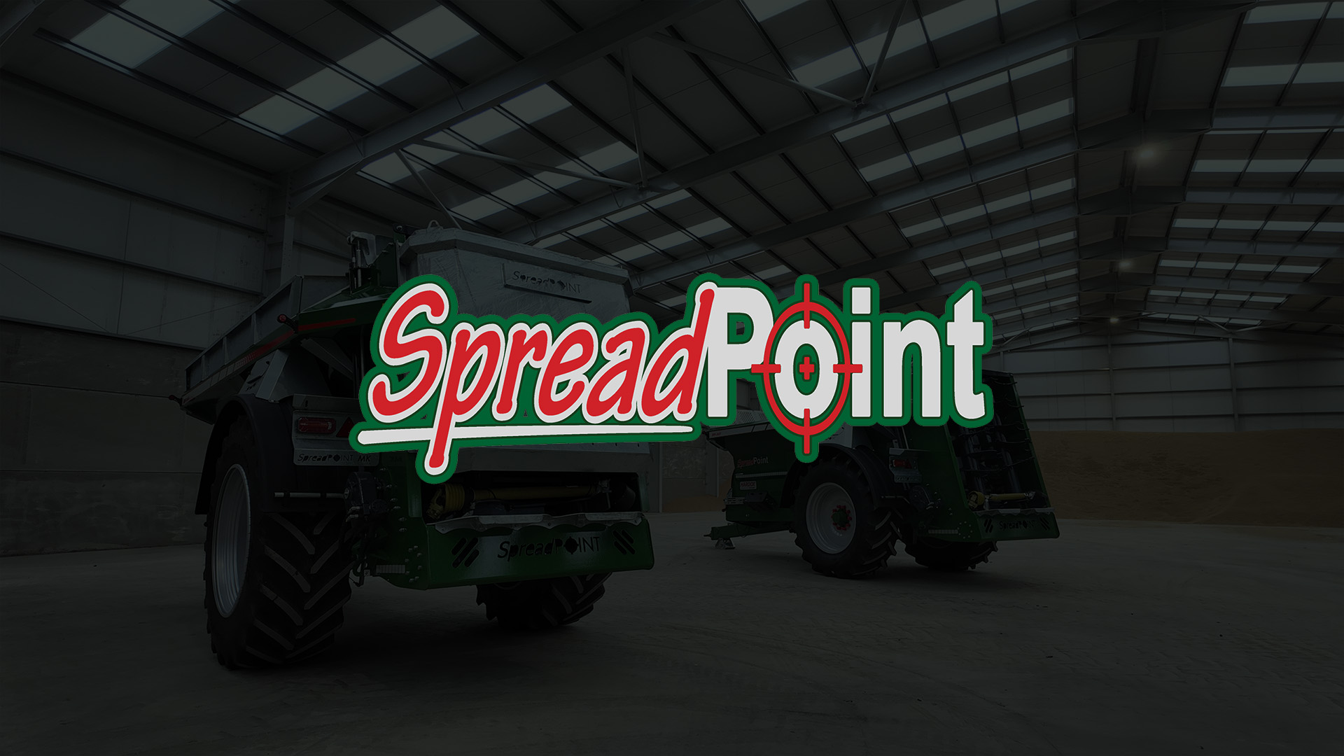 Industrial agricultural spreader machines inside a large warehouse with a high ceiling, featuring the large colorful SpreadPoint logo overlaid in the center.