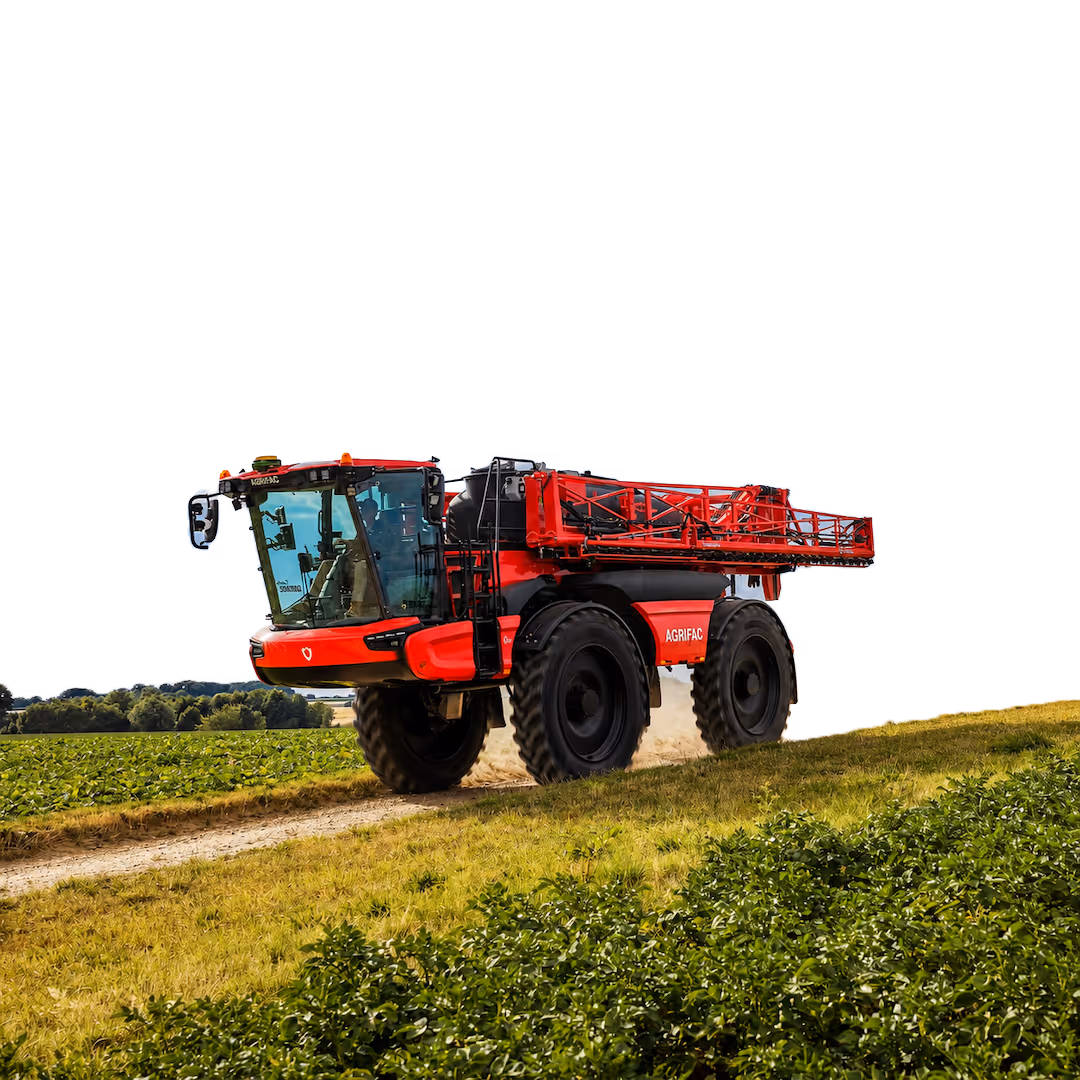 Red Agrifac self-propelled agricultural sprayer with large tires driving on a dirt path alongside green crops in a field under a clear sky.