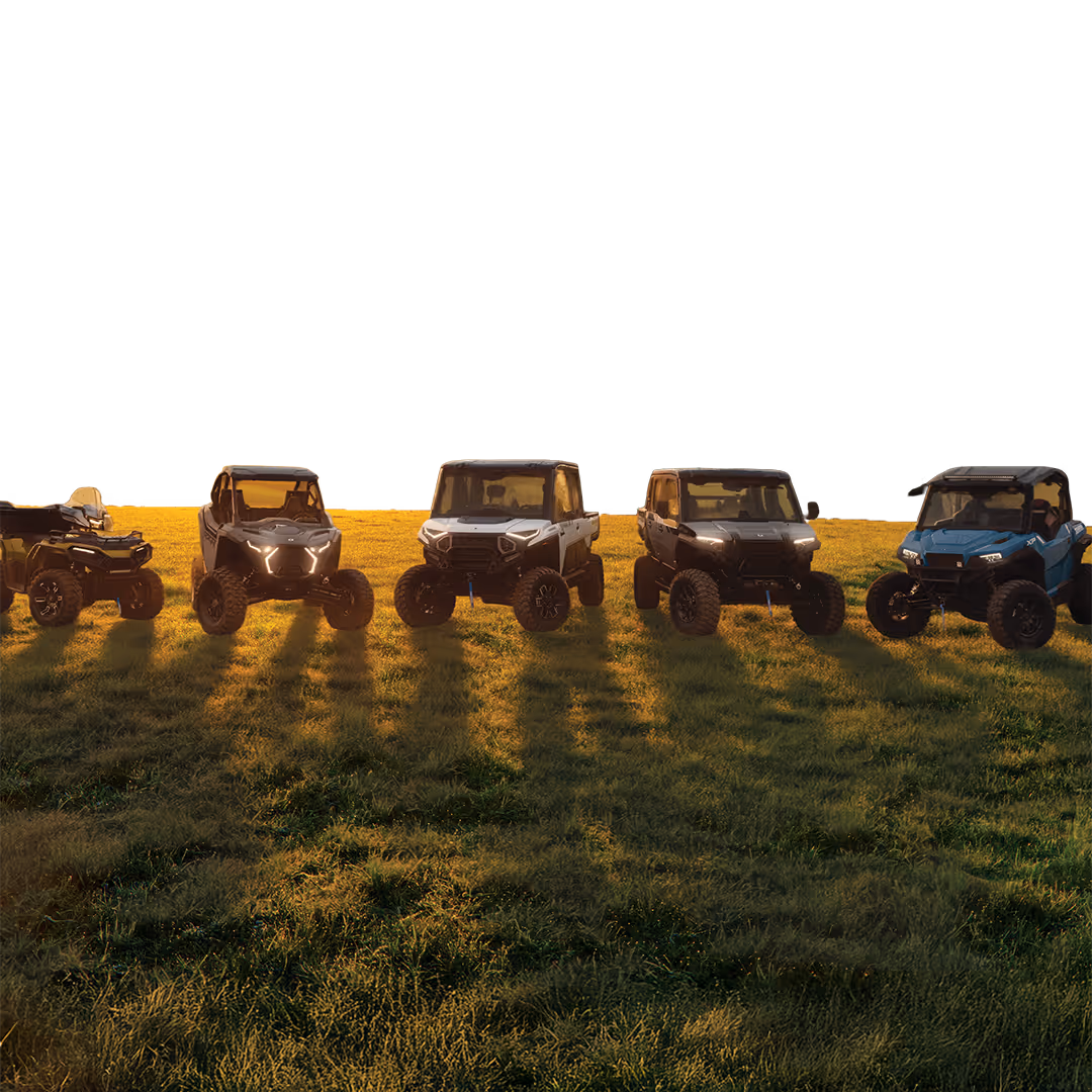 Five off-road utility vehicles parked side by side on grass at sunset, casting long shadows.