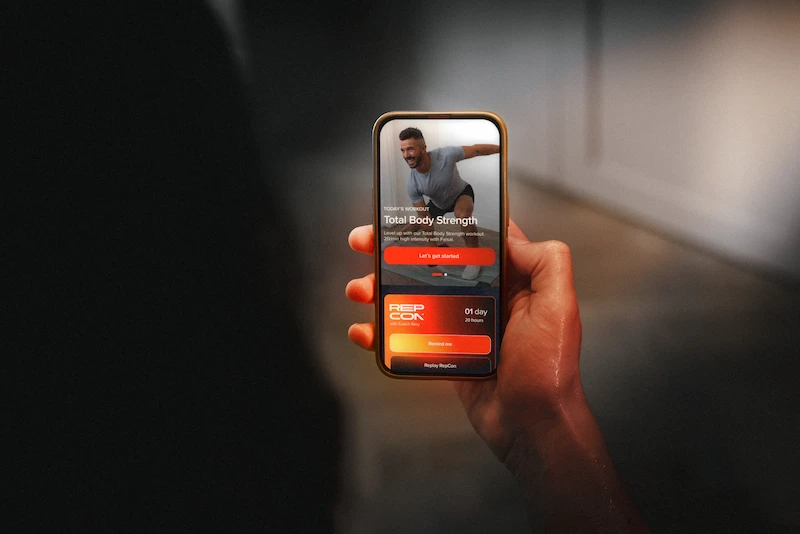 Person holding phone showing a workout app screen for Total Body Strength and RepCon timer.