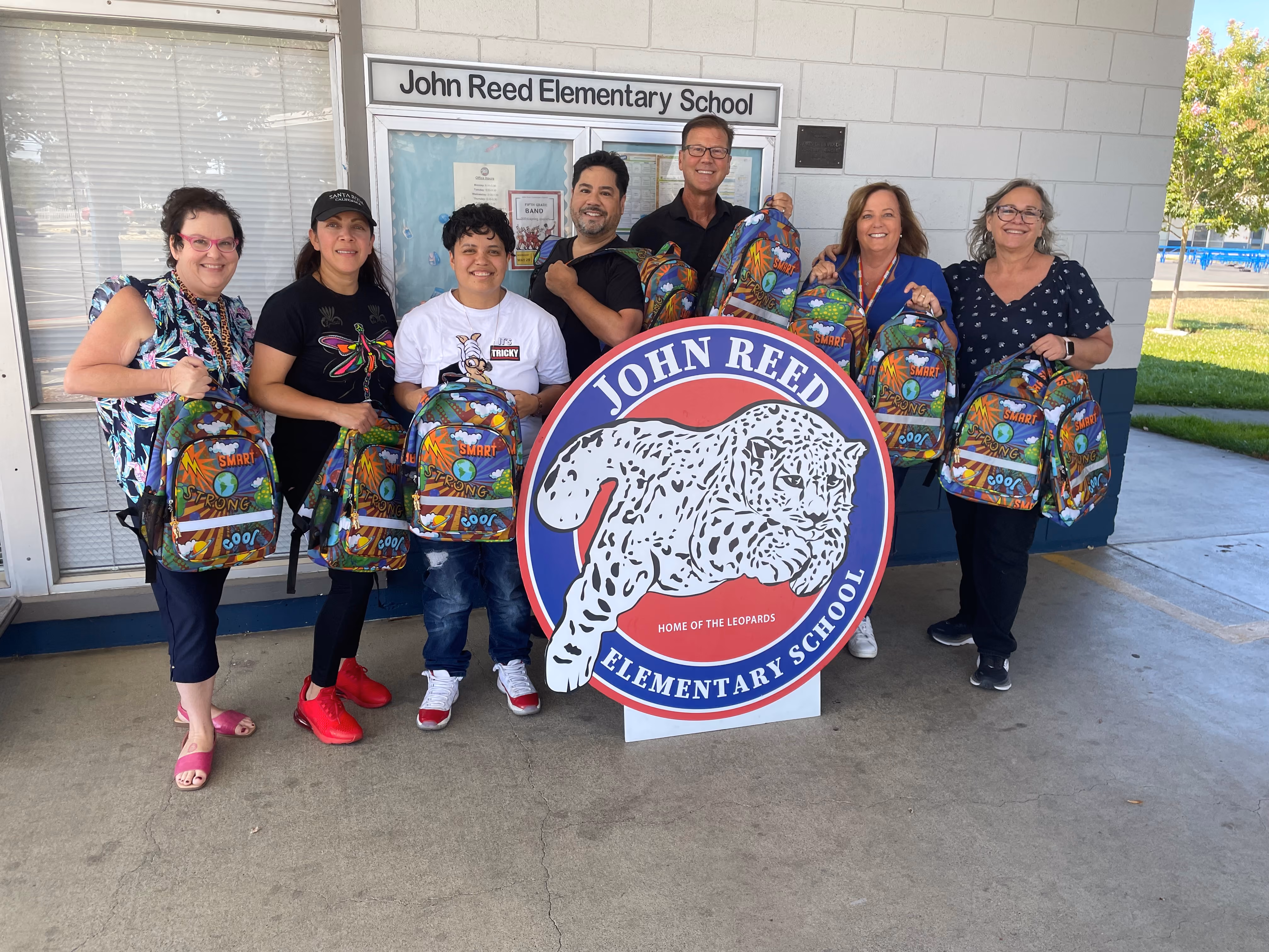 A photograph of several people holding donated backpacks