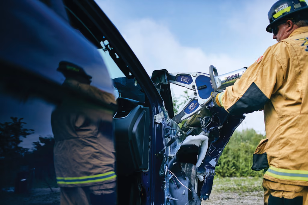 A fire fighter using the jaws of life on a car