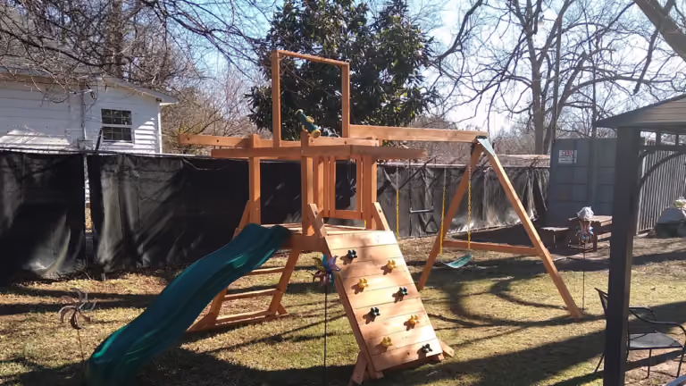 A photograph of a wood playground in a backyard