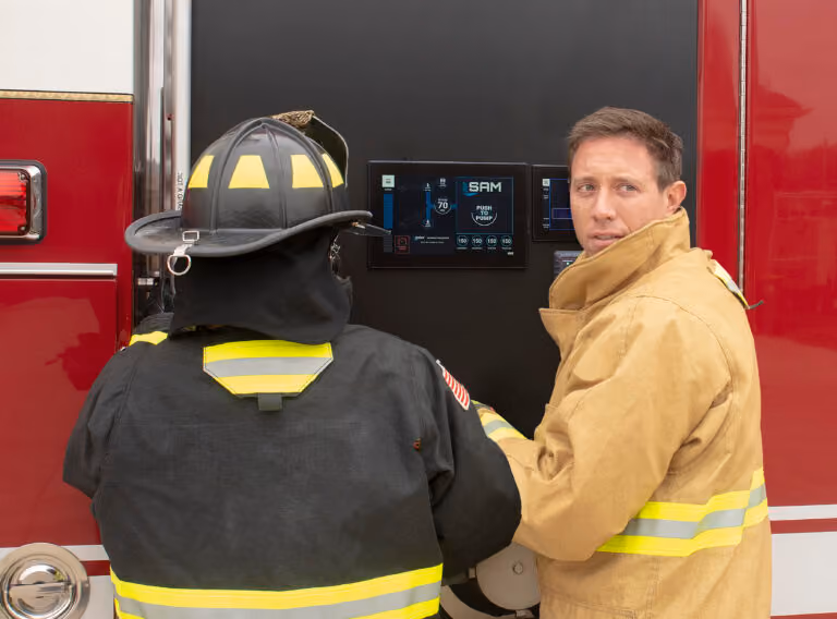 Two fire fighters standing at a SAM terminal